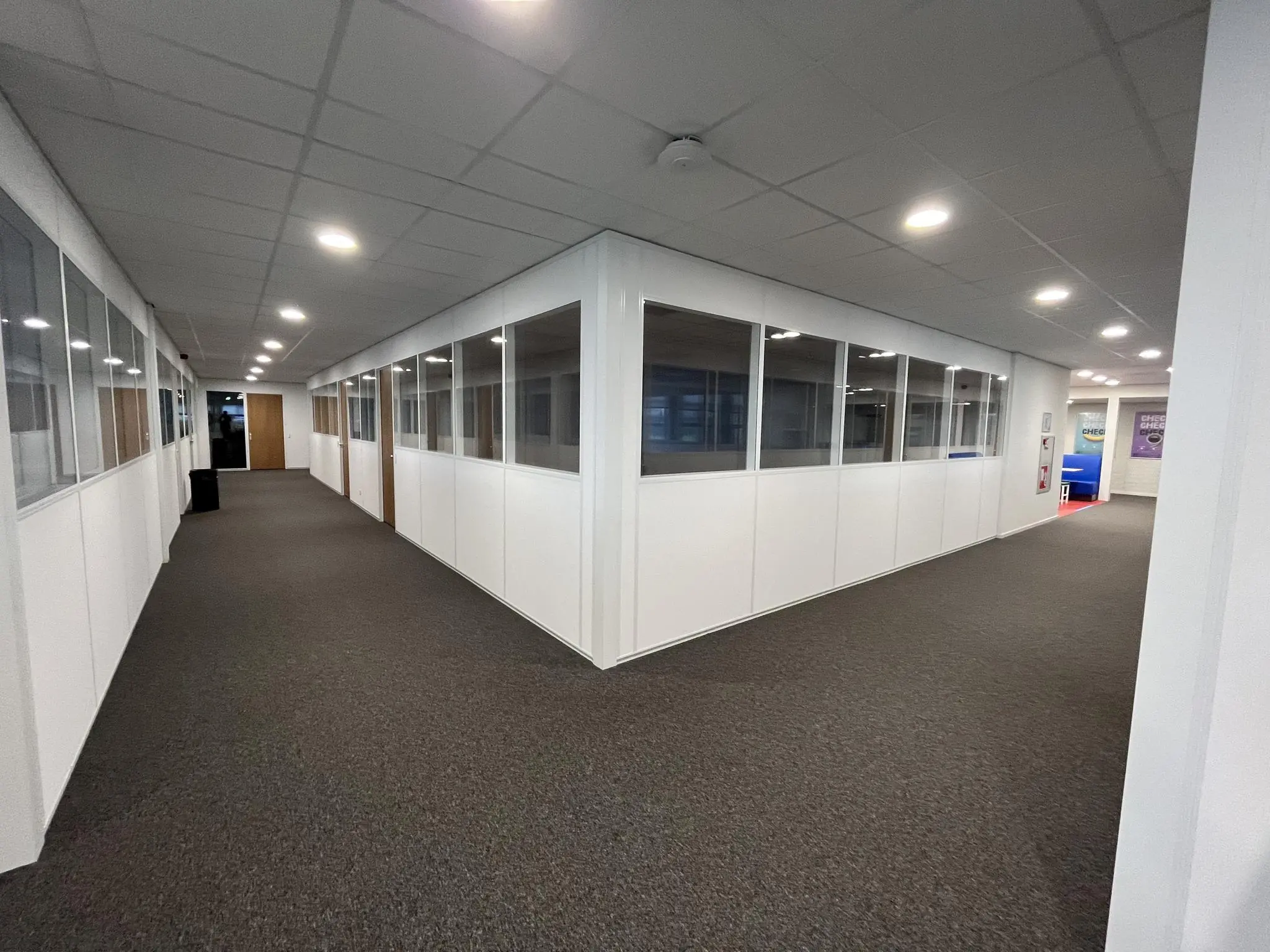 Kantoorgang met witte wanden, glazen ramen en bruine deuren in een bedrijfsverzamelgebouw aan de Niels Bohrweg.